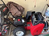 Side view of red snowblower showing housing, chute and wheels