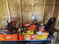 Wide shot of three boxes containing assorted tools and supplies, plywood wall background.
