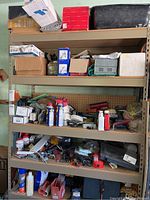 Wide view of three shelves filled with various tools, paint brushes, cleaners, padlocks, and small boxes with parts.
