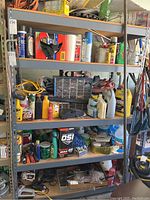 Wide view of five metal shelves filled with assorted tools, hardware, cleaners, gardening supplies, jumper cables, and more.