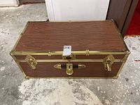 Top view of locking veneered OSB trunk showing wood grain surface and brass-tone edges with latches and lock.