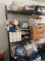 Full view of the black wire shelving unit with various boxes and bags placed on shelves, showing overall dimensions and condition of the unit.