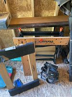Black & Decker Workmate workbench folded, along with furniture dolly and tool bag stored in a shed.