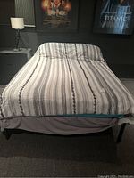 Front view of assembled bed frame with mattress and bedding in a room with carpeted floor and movie posters