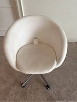Front view of white office chair showing round seat and minor stains.