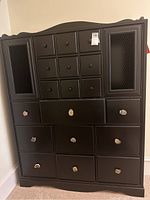 Full front view of the black dresser showing multiple drawers and cabinet doors.
