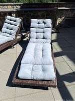Front view of a single Outsunny patio lounger with light grey tufted cushion on brown rattan-style frame in sunlight outside.