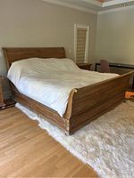 Bed frame installed in room showing headboard, footboard and side rails with bedding