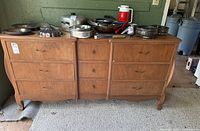 Front view of wooden cabinet showing nine drawers and some kitchen items on top (not included).