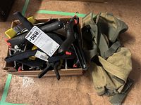 Box filled with various clamps and an adjacent canvas tool bag.