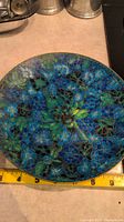 Top view of first cloisonné plate, showing detailed blue, green, and yellow floral design with metal wire outlining.