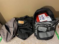Lot of an emergency supply kit with first aid kit inside a backpack and two additional handbags.