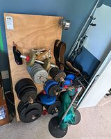 Full view of wooden board storage with adjustable dumbbells, weight plates, belts, bars, and stands