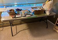 Full side view of folding table showing items on top, rounded corners, window background.