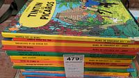 Stack of 11 French Tintin children's books seen from the side showing spines with titles and a price tag from MaxSold.