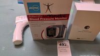 Atoma blood pressure monitor in box with thermometer behind.
