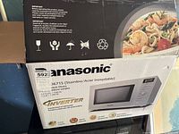Box showing Panasonic NN-SD671S microwave oven model with inverter technology and 1.2 cu. ft capacity, 1200 W power.