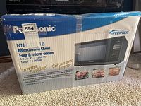 Photo of microwave oven box showing model number NN-ST681B, capacity 1.2 cubic feet, power 1200 watts, inverter cooking technology branding.