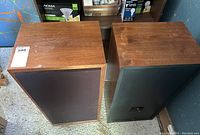 Pair of Acoustic Research wooden speakers side-by-side showing top and front with fabric grills