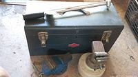 Metal toolbox with torque wrench laid on top, showing two small vises placed in front of toolbox