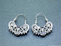 Pair of Balinese hoop earrings with intricate detailed scrollwork and small beads along the edge.