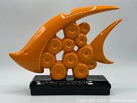 Front and side view of bright orange ceramic tropical fish decor on black base