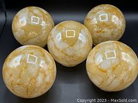 Top-down view of five glass light globe shades showing the yellow and white mottled marble design pattern.