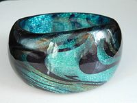Front angled view showing overall chunky lucite bracelet with vibrant turquoise green, glitter included, and smooth black swirl design.