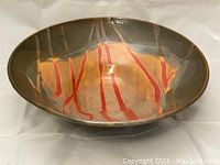 Front angled view showing the bowl interior with warm ochre, brown, and red stripe patterns and a darker outer glaze.