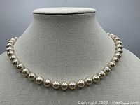 Frontal view of the full pearl necklace displayed on a fabric bust showing the rounded cream pearls with a lustrous finish.