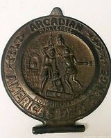 Close-up photo of the antique Arcadian Malleable cast iron range door cover featuring raised figures and text.