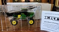 Side view of the green and yellow die cast John Deere 4710 sprayer tractor in clear plastic box with certificate of authenticity.