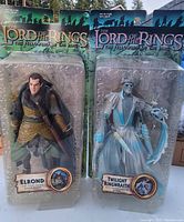 Front view of two Lord of the Rings action figures in original plastic blister packaging, labeled Elrond and Twilight Ringwraith.