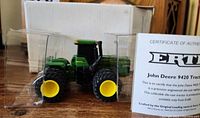 John Deere 9420 4WD tractor die-cast model inside clear plastic display case with Certificate of Authenticity and original box behind.