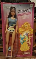 Full front view of the Uneeda Donna doll sealed in original pink packaging wearing swimsuit, standing 11.5 inches tall.