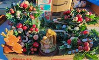 Photo shows 5 plastic Christmas wreaths with red berries and holly leaves, and a vintage music box with a nativity scene.