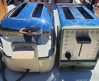 Two vintage General Electric toasters side by side; one with a chrome body and white base, the other with decorative front panel and controls.