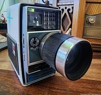 Front angled view showing lens with focus and aperture controls, flash socket and front dials.