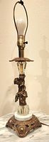 Full view of the lamp showing the entire height from brass cherub, marble base, ornate brass feet, and lamp socket with bulb