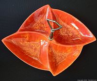 Top view showing the three divided triangular sections with floral patterns and central metal handle of the orange ceramic dish.