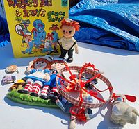 Overview of Raggedy Ann and Andy lot items including wall hanging, vinyl record, belt buckles, plush doll and crib mobile.