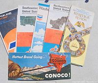 Vintage road maps fanned out showing various states and branded oil company maps from the 1970s.