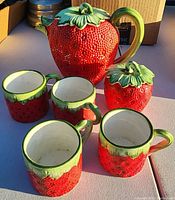 Full set view under sunlight showing tea pot, sugar container, and four cups in strawberry design