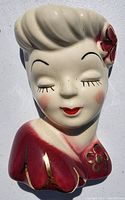 Front view of vintage lady wall planter bust showing painted facial features, red and gold floral blouse, and hair with flower detail.