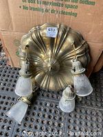 Top view of antique brass light canopy and four frosted ribbed glass hanging light shades placed on the ground.