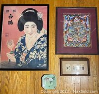 Photo of four Asian art items: large women print, colorful ink artwork framed in maroon, three window wood framed Japanese characters, and square fish decorative plate on floor