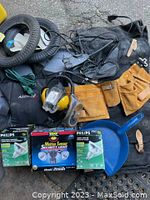 Wide view of assorted tool hardware including tires, tool belt, ear protection, safety glasses, pan, cords and hardware items.