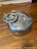Left side view of Babson Bros The Surge Milker showing round metal tank with handle and lid with holes for nipple contacts.