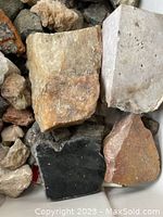 Close-up view of various rough stones including quartz and other minerals with different colors and textures