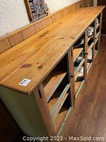 Side angle view of the large antique kitchen cabinet showing the pine wood top and four doors with vintage handles.